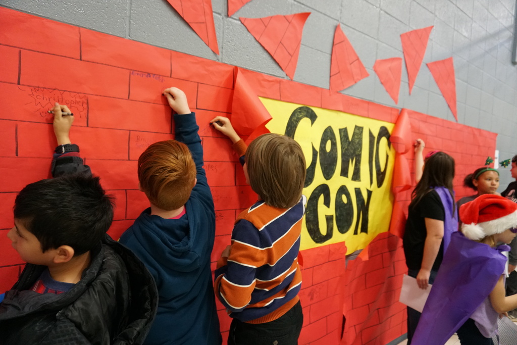 Students autograph the ComicCon wall