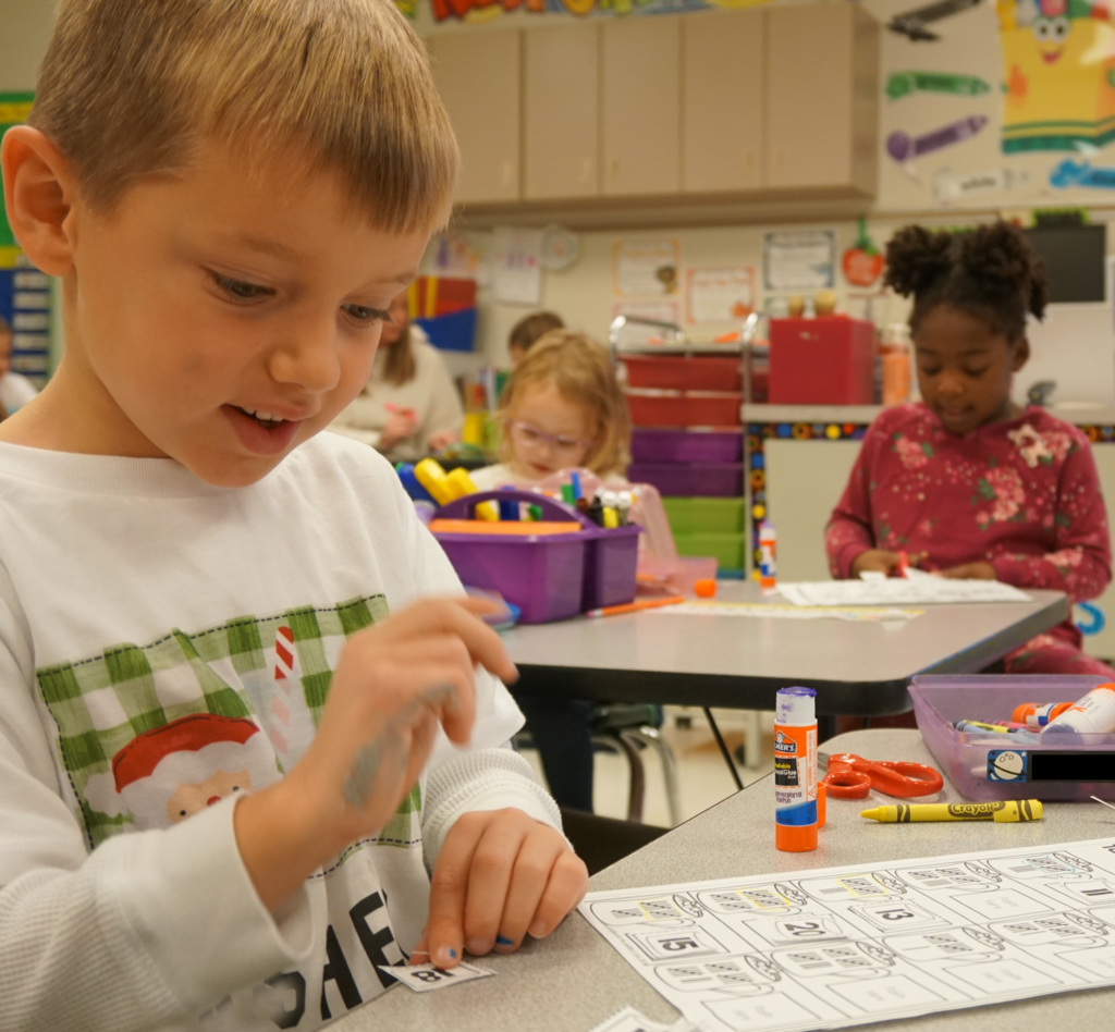 Kindergarteners hard at work cutting and gluing numbers into sequence and solving problems