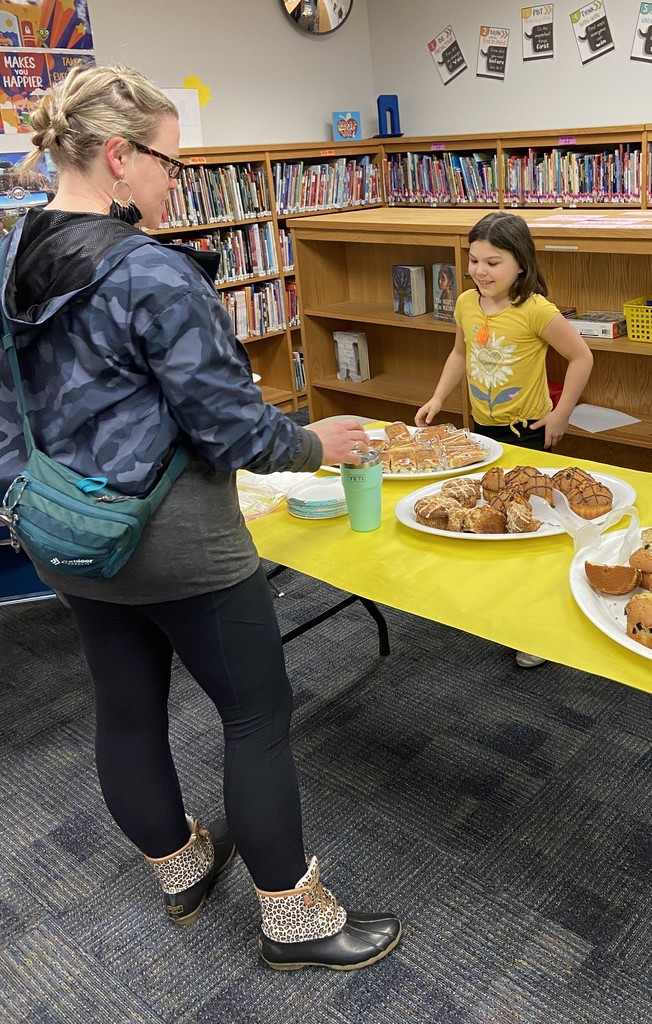 A student helps a teacher make her breakfast selection.