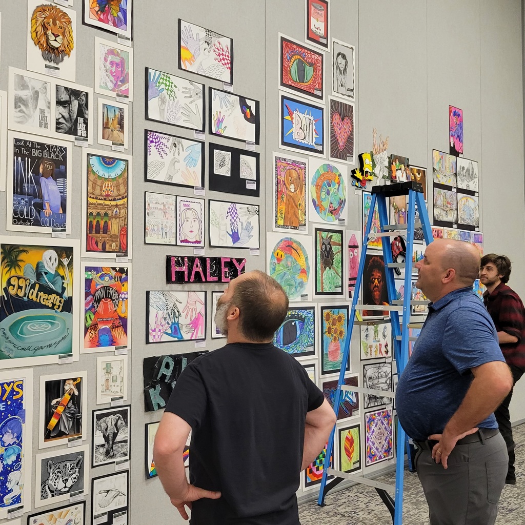 Art teachers take in the work from each others' students as the show's display comes together