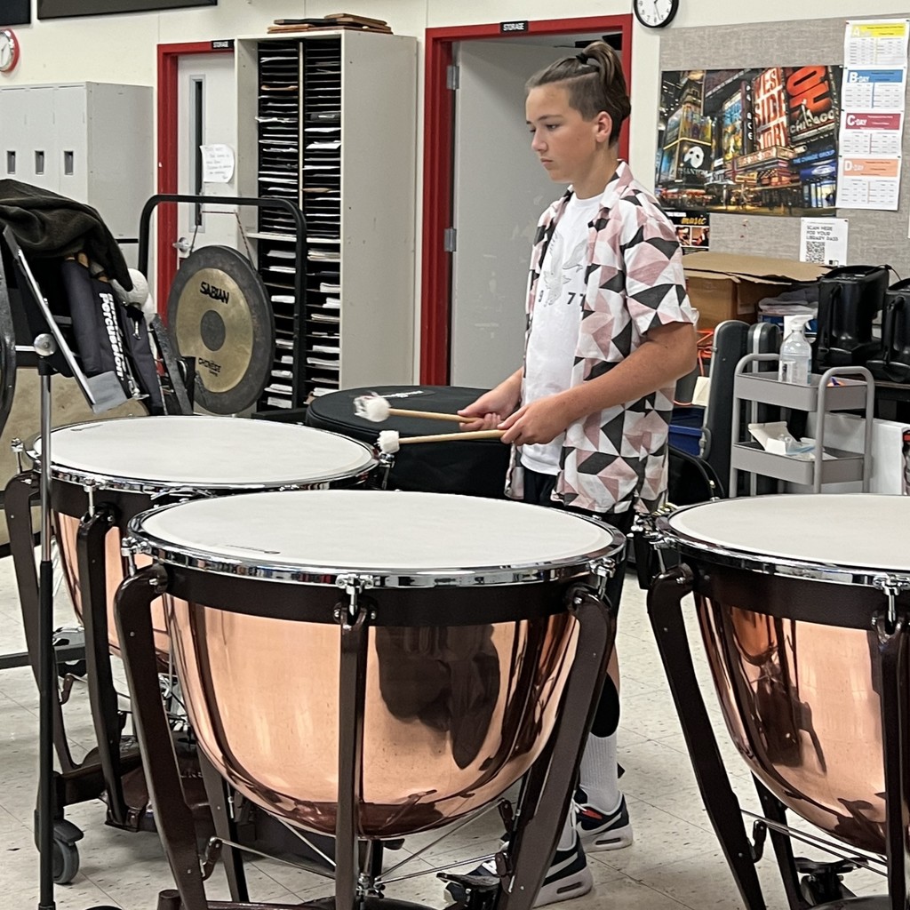 A percussionist steps up to the three shiny, copper colored tympani in the FZS band room