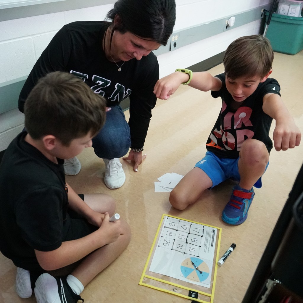 Boy celebrates solving a problem with his teacher. Third graders work cooperatively to capture squares.