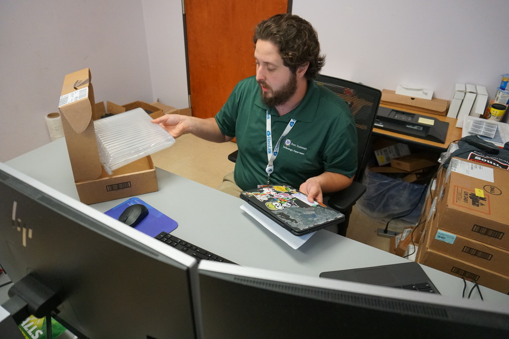In his quiet office, middle school IT Pro repairs student chromebook
