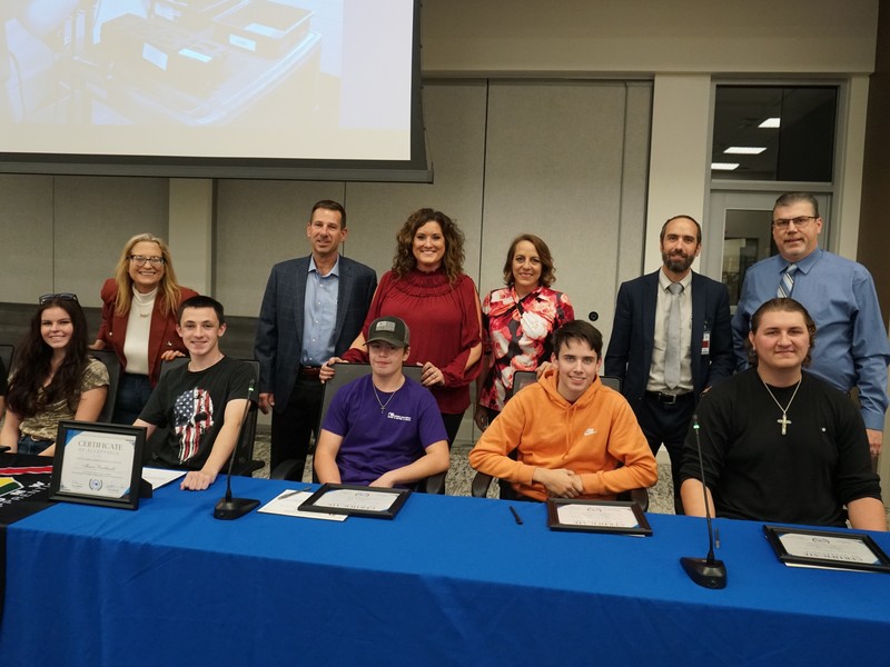 National Cart, Co. officials pose at the signing table with their five new Zumwalt apprentices.