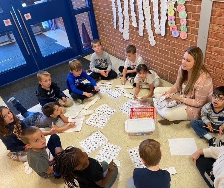 Elementary students spread work out on the floor with their teacher