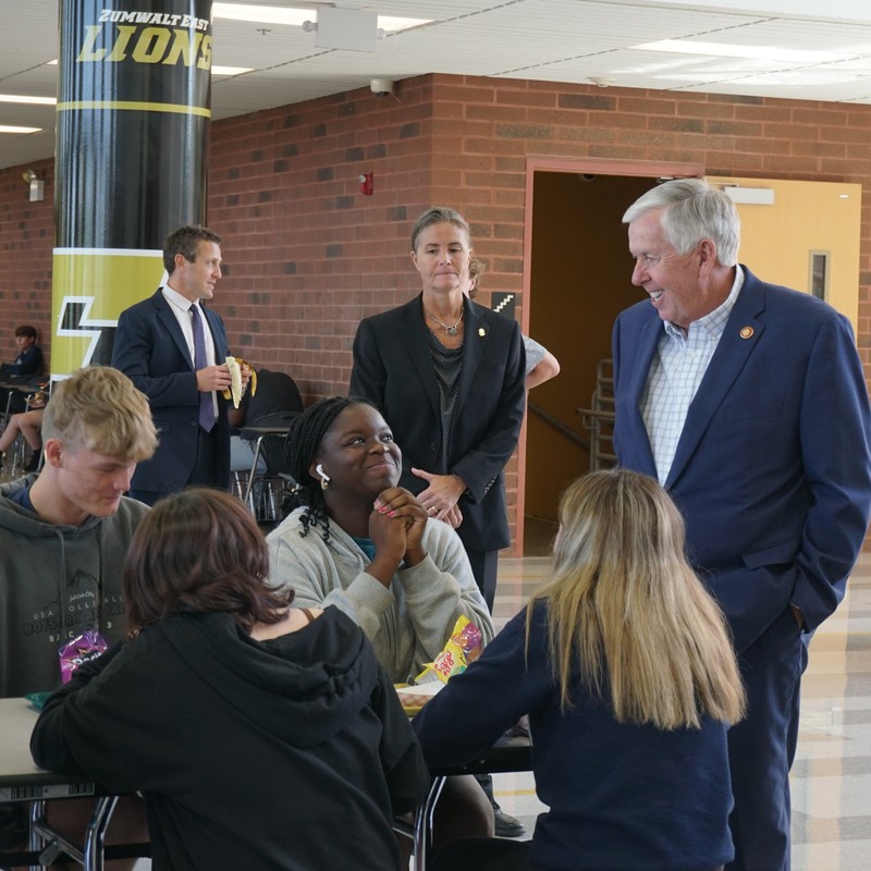The governor shares a laugh with students in a quick visit in the cafeteria to check on lunch.